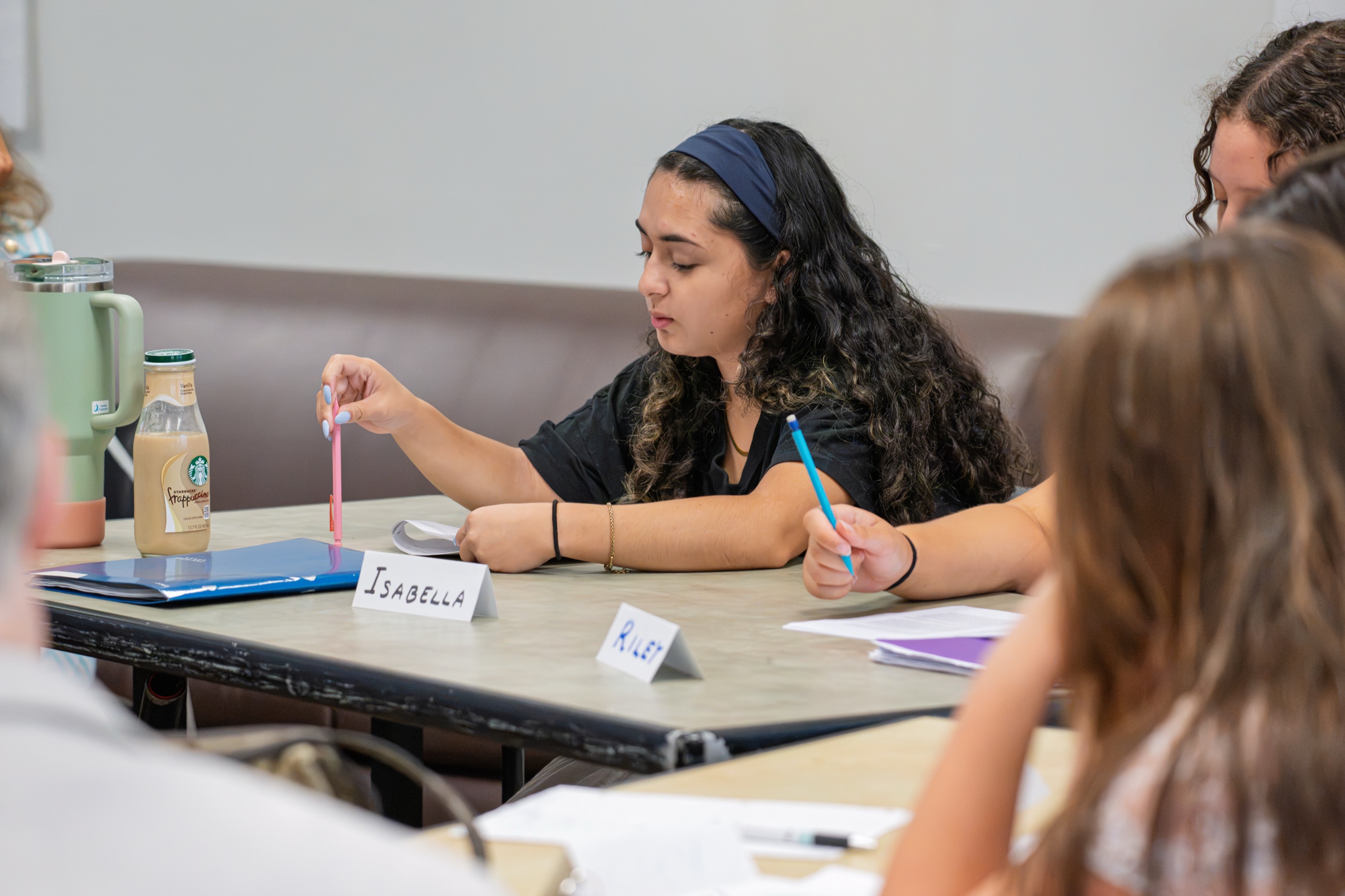 A seminar participant marking up her text, with handwritten name cards on the table in front of her