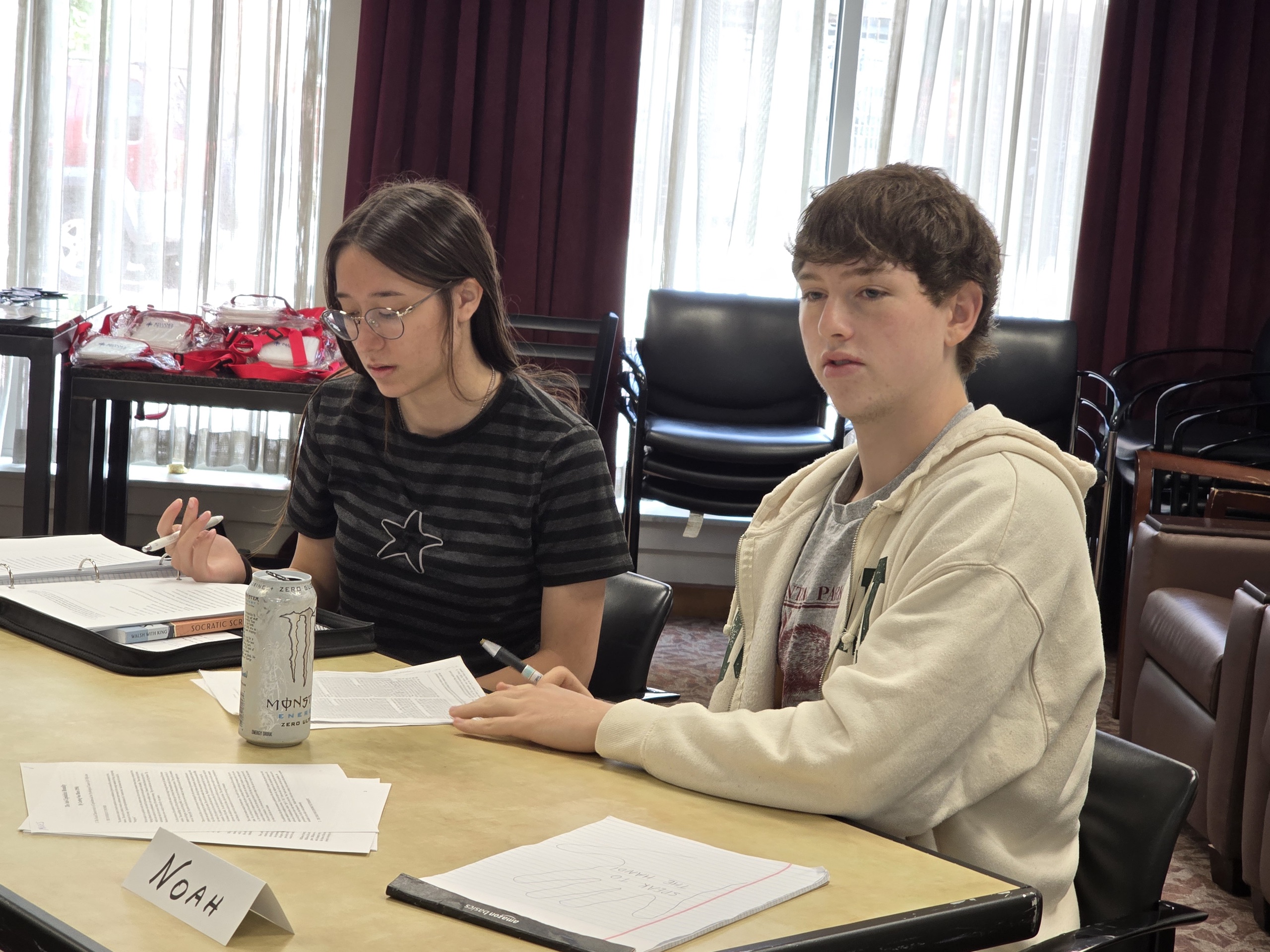 Two Great Connections Seminar participants at a table with the printed readings and a Socratic Seminar binder open in front of them